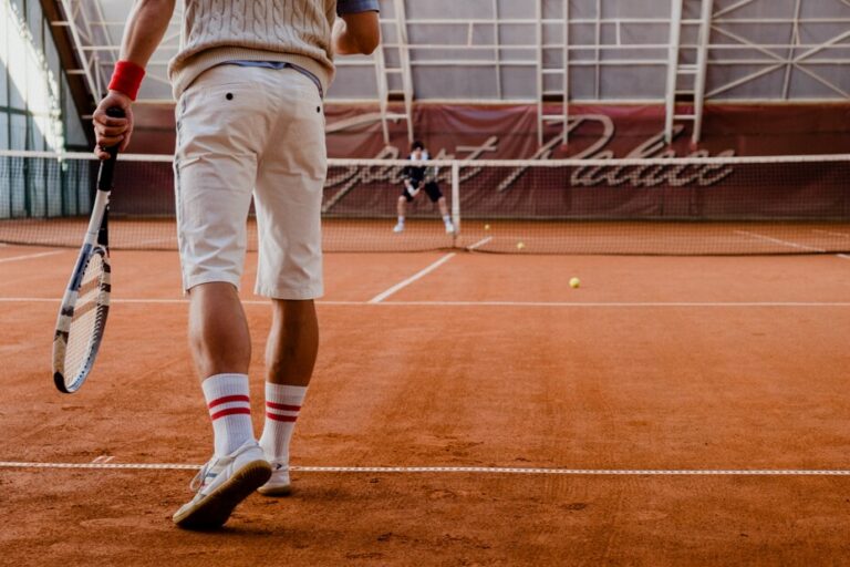 Two people playing tennis on a clay court
